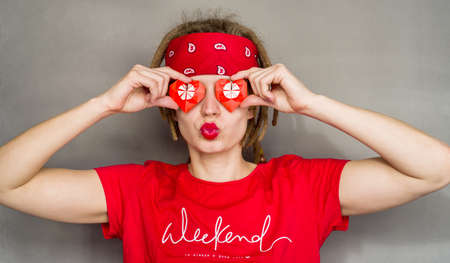 young caucasian hipster woman with dreadlocks and red headband covering her eyes with origami heartsの写真素材