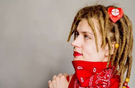 young caucasian hipster woman with dreadlocks and an origami heart in her hair looking forwardの写真素材