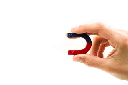 Magnet in female hand on a white backgroundの写真素材