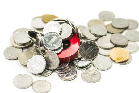 magnet surrounded by metal coins on whiteの写真素材