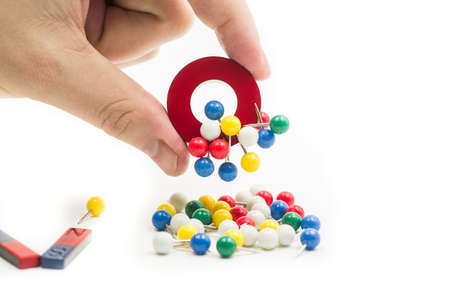 man hand holding a magnet attracting metal pinsの写真素材