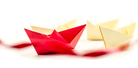 leadership concept. origami paper boat leading white ships crossing red finish line. Rivalry, business, success and efficiency conceptの写真素材