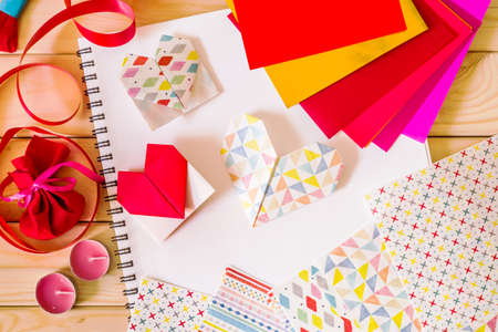 hand made origami paper hearts for valentine's day surrounded by origami paper, candles, giftsの写真素材