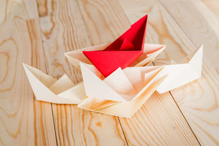 leadership concept. origami paper boat leading white ships crossing red finish line. Rivalry, business, success and efficiency conceptの写真素材