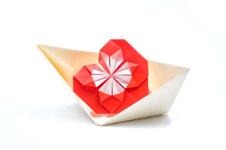 one red origami hand made heart in the paper boat isolated on white backgroundの写真素材