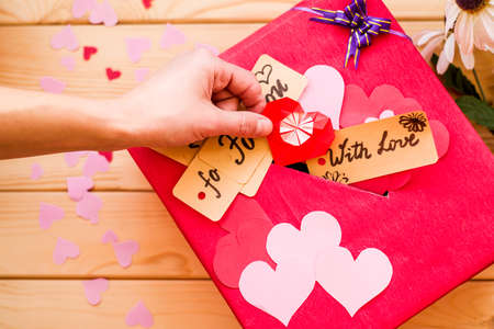 womans hand putting an origami heart to valentines day red gift box with a gap for paper valentinesの写真素材