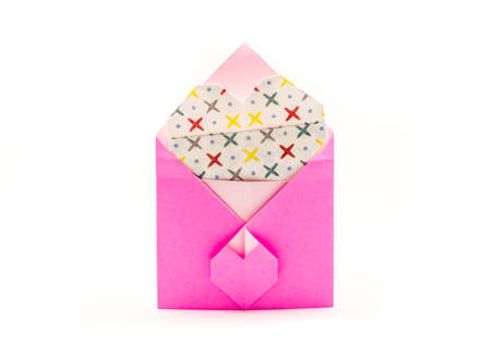 pink origami envelope with white paper heart isolated on whiteの写真素材