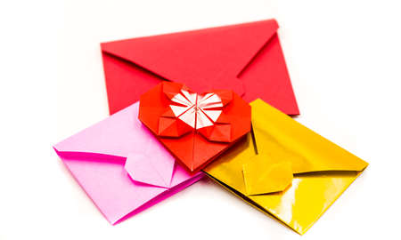 pile of colorful origami paper envelopes and red heart isolated on whiteの写真素材