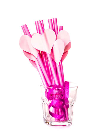 valentine's day holiday. pink and red sipping straws in a glass isolatedon white background.bright sipping straws for party or birthdayの写真素材