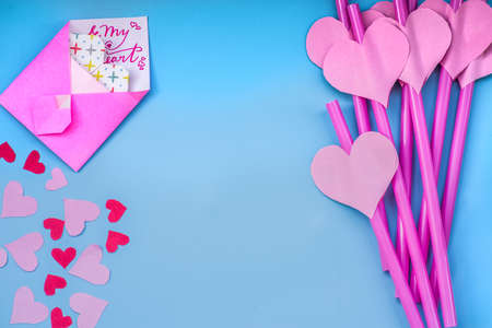 valentines day holiday. bright pink and blue drinking straws with hearts, envelopes and a pink ribbon on blue.bright sipping straws for party or birthdayの写真素材