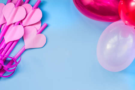 valentines day holiday. bright pink drinking straws with hearts and colorful balloons on blue background.bright sipping straws for party or birthdayの写真素材