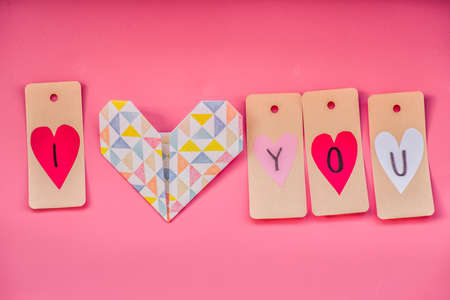 valentines day holiday. lovely hand made decorations for a valentine day on pink background. i love you labels and origami heartの写真素材