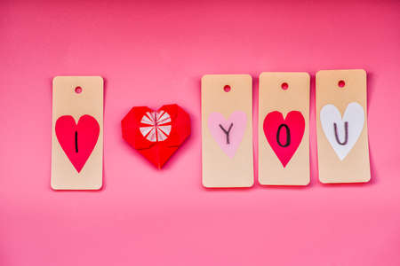 valentines day holiday. lovely hand made decorations for a valentine day on pink background. i love you labels and origami heartの写真素材