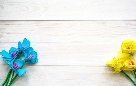 women's day cocept. yellow and blue spring paper flowers on white wooden background.の写真素材