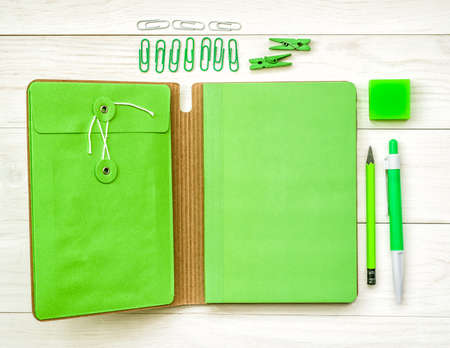 fresh green stationary. green notebook with eraser, pen,pencil and paper clips on white wooden backgroundの写真素材