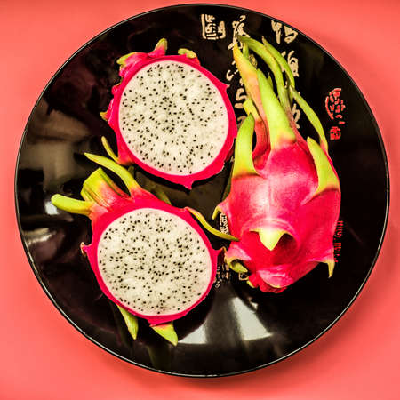 Dragon fruit on a black plate isolated on black background flat lay top viewの写真素材