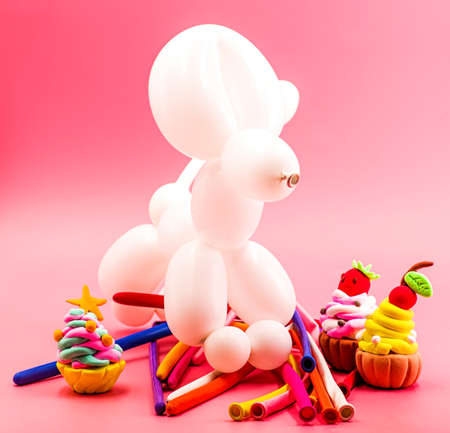 party concept. balloon dog, clay cupcakes and balloons on bright pink backgroundの写真素材