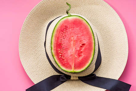 creative layout of fruit. a watermelon in a summer hat on pink backgroundの写真素材