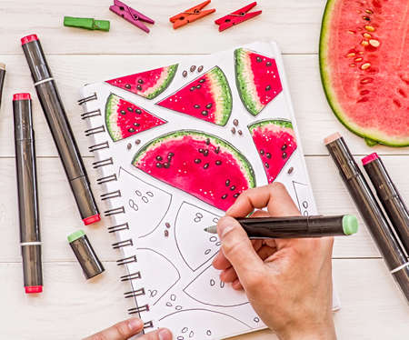 drawing a bright watermelon sketch with markers on wooden backgroundの写真素材