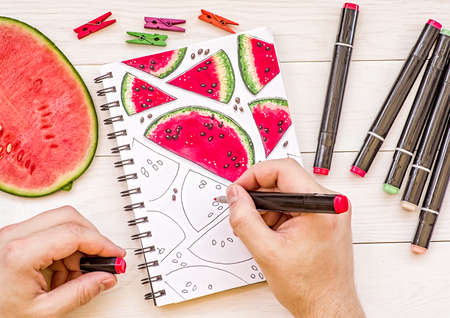 drawing a bright watermelon sketch with markers on wooden backgroundの写真素材