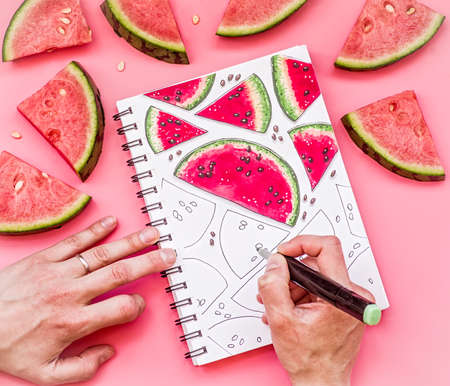 woman hands drawing a watermelon pattern sketch on pink background with markers. bright food sketch decorated with watermelon piecesの写真素材