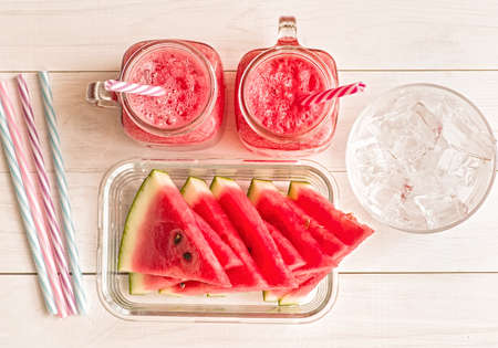 summer drinks concept. watermelon slices and smoothies in mason jar on white wooden background top view.の写真素材