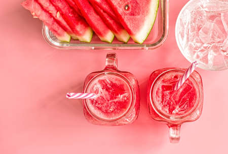 summer drinks concept. watermelon slices and smoothies in mason jar on pink background top view.の写真素材