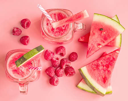 summer drinks concept. watermelon slices and smoothies in mason jar on pink background top view.