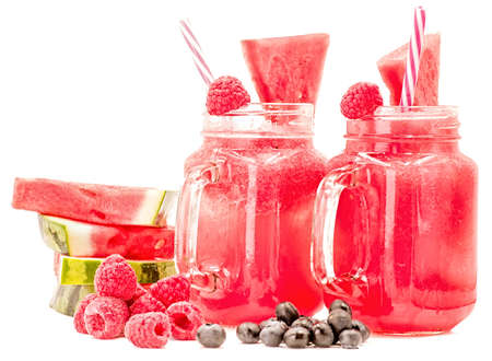 watermelon smoothie in a mason jar decorated with a slice of watermelon, raspberries ans ice cubes isolated on white background. fruit smoothie with a drinking straw isolatedの写真素材