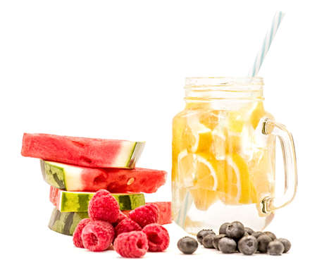 lemonade in a mason jar with a drinking straw decorated with slices of watermelon,raspberries and blueberries isolated on whiteの写真素材