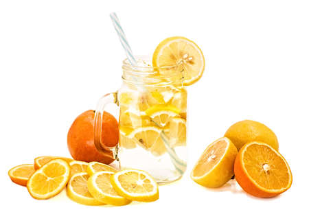 lemonade in a mason jar with a drinking straw decorated with slices of lemon and orange isolated on whiteの写真素材