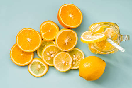 lemonade in a mason jar with a drinking straw decorated with slices of citrus oranges and lemons top view on blueの写真素材