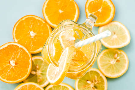 lemonade in a mason jar with a drinking straw decorated with slices of citrus oranges and lemons top view on blueの写真素材