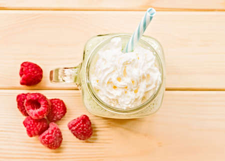kiwi and banana milkshake in mason jar with creme and sipping straw top view flat lay on wooden rustic backgroundの写真素材