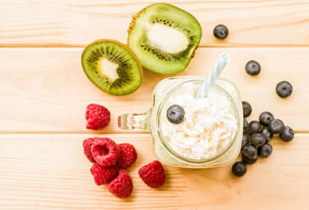 kiwi and banana milkshake in mason jar with creme and sipping straw top view flat lay on wooden rustic backgroundの写真素材