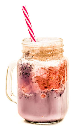 blueberry and raspberry milkshake in mason jar with drinking straw isolated on whiteの写真素材