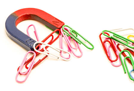 U-shaped red and blue magnet attracting paper clips isolated on white backgroundの写真素材