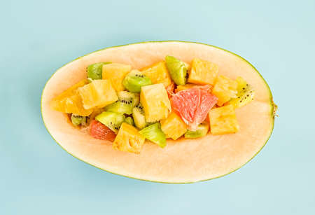 summer fruit concept. melon half with fresh fruit salad inside on blue background flat lay top viewの写真素材