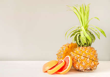 creative layout. summer fruit concept. cut pineapple and grapefruit slices on white wood with grey...