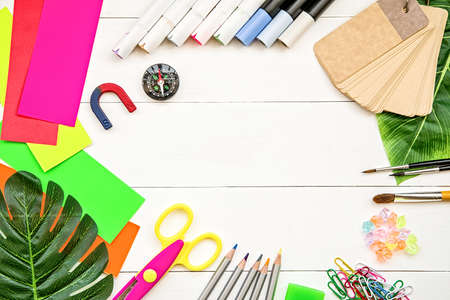 back to school concept. various stationary and tropical leaves on white wooden background. objects for arts and drawingの写真素材