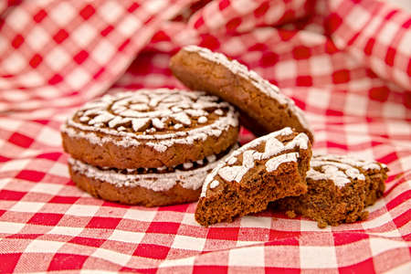 pile of gingerbread cookies with two broken pieces on red and white tradational tablecloth