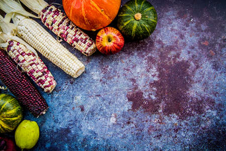 various corn cobs, fruits and vegetables on dark background. autumn harvesting concept with copy spaceの写真素材