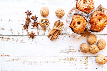 thanksgiving day concept. backed apples in foil with walnuts and cinnamon on white wooden background top view flat layの写真素材