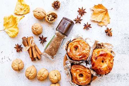 thanksgiving day concept. backed apples in foil with walnuts and cinnamon on white wooden background top view flat layの写真素材