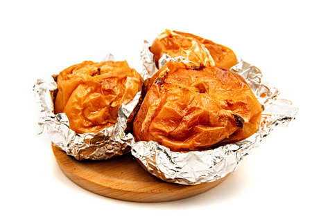 thanksgiving and christmas concept. Baked apples in aluminum foil on wooden plate isolated on whiteの写真素材