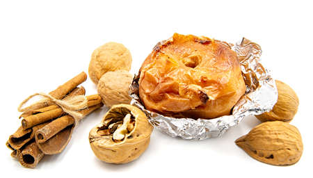 thanksgiving and christmas concept. Baked apple in aluminum foil with walnuts and cinnamon isolated on whiteの写真素材