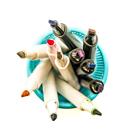 colorful markers in a blue holder, school or office supplies isolated on white top view