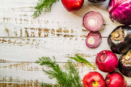 raw purple vegetables and fruit on white wooden background top view