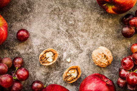 purple and red fruit: grapes, apples and walnuts top view on dark background flat lay. Healthy food or diet conceptの写真素材