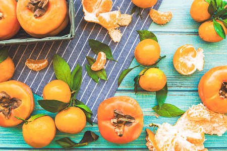 persimmons and tangerines on blue wooden background top viewの写真素材